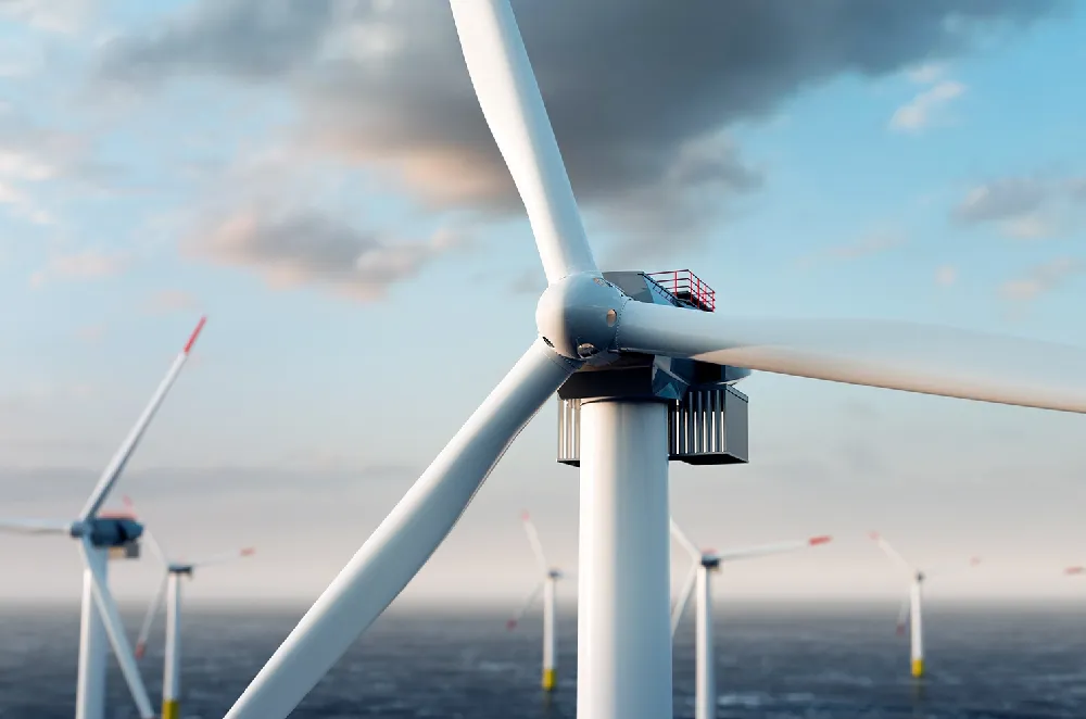 Offshore wind turbines generating renewable energy at sea during early evening. The image shows multiple large white wind turbines with red-tipped blades against a blue sky with light clouds, highlighting sustainable power sources in the UK.